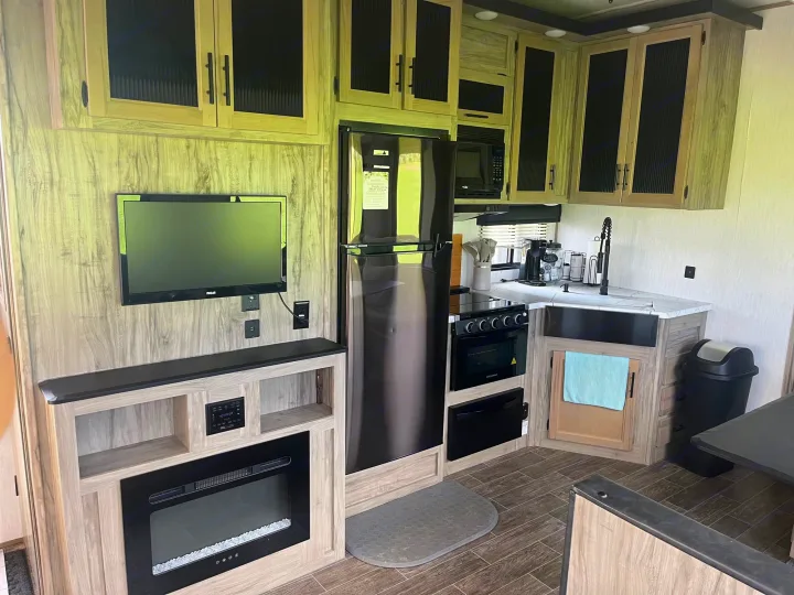 Modern RV rental interior showcasing a full kitchen, living area with TV & fireplace, and ample storage.. Forest River Cherokee Arctic Wolf 2021