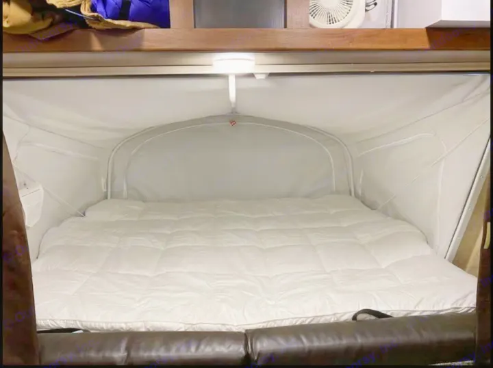 Inside an RV rental: a plush pop-out bed with a white comforter & integrated light. Enjoy comfy sleep on your camper adventure.. Jayco Jay Feather 2017