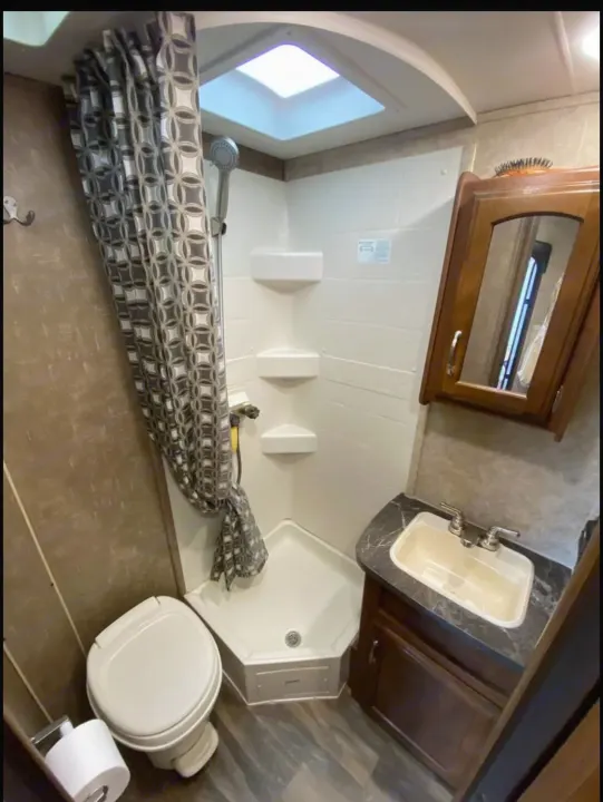 Experience an RV rental with this compact, functional bathroom featuring a corner shower, toilet, sink vanity, and skylight.. Jayco Jay Feather 2017