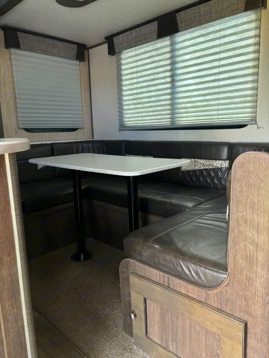 Spacious RV rental dinette with comfortable black leatherette seating, a modern table, and privacy blinds.. Cruiser RV MPG Ultra Lite 2019