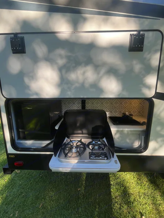 RV rental with convenient outdoor kitchen: FlameKing cooktop, Hotpoint fridge, and sink for easy camping.. Heartland RVs North Trail 2022