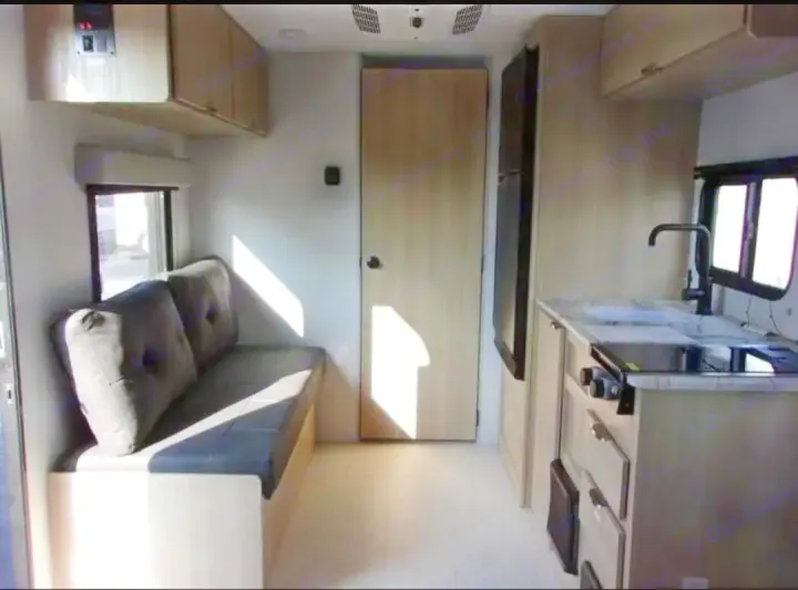 RV rental interior: A compact living space with a kitchen, sofa, and fridge. Sunlight brightens the functional layout.. Forest River Salem FSX  164RBLE 2024