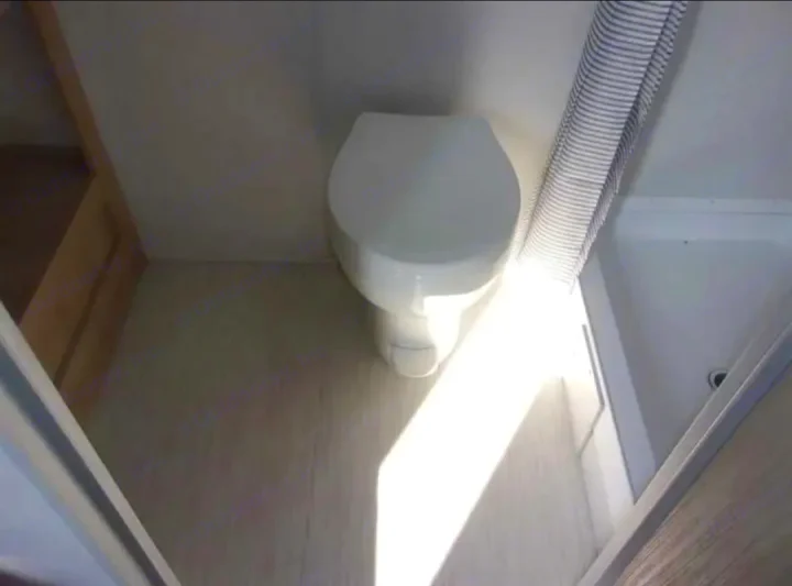 RV rental: Bright, compact bathroom features a clean toilet, striped shower curtain, and ample sunlight.. Forest River Salem FSX  164RBLE 2024