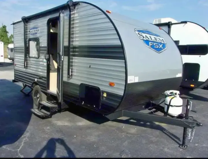 Grey and black Salem FSX travel trailer with open door, steps, and propane tank, ready for RV rental adventures.. Forest River Salem FSX  164RBLE 2024