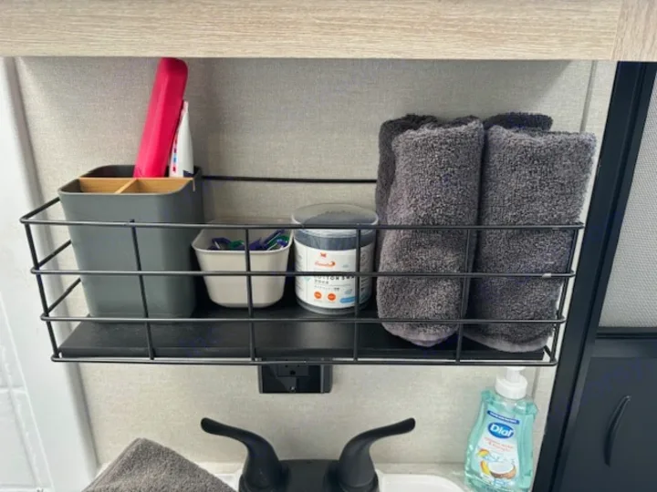 RV rental bathroom organization: shelf with toiletries, towels, and soap by the sink, maximizing small space.. Forest River Aurora Aurora 2024