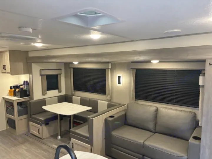 Spacious RV rental interior with modern living and dining areas, featuring a dinette, sofa, and ample lighting.. Forest River Aurora Aurora 2024