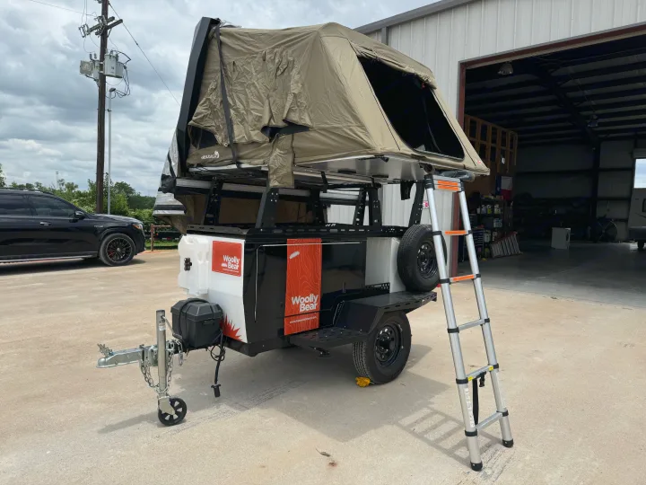 A "Woolly Bear" overland trailer with a rooftop tent and ladder, ideal for your next RV rental adventure.. taxa Woolly Bear 2017