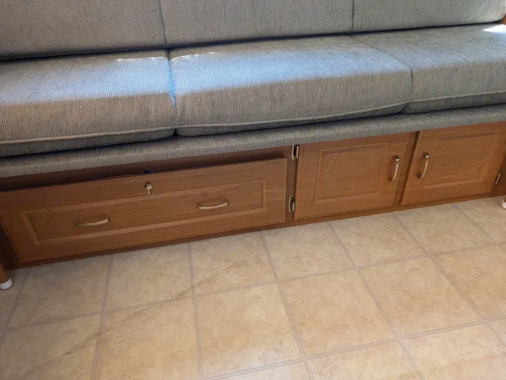RV rental interior featuring gray fabric bench seating over wooden storage drawers & cabinets on a light tiled floor.. Coleman Utah 2003