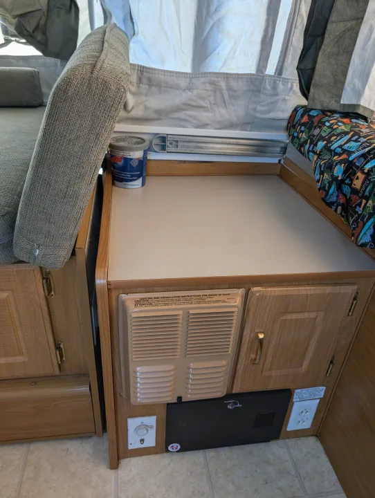 Cozy RV rental interior: bench seating, counter, heater, and electrical outlets, ready for your next camper adventure.. Coleman Utah 2003