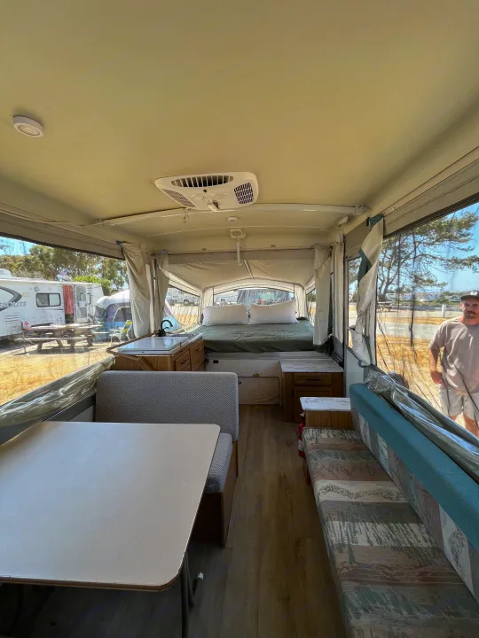 Spacious pop-up RV rental interior with a cozy bed, kitchen, and dining area. Perfect for camping adventures.. Coleman Destiny Cheyenne 1998