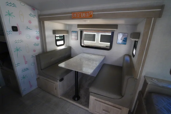 RV rental interior: A bright dinette with a beach-themed accent wall and comfortable seating for your adventures.. Forest River Rockwood 2021