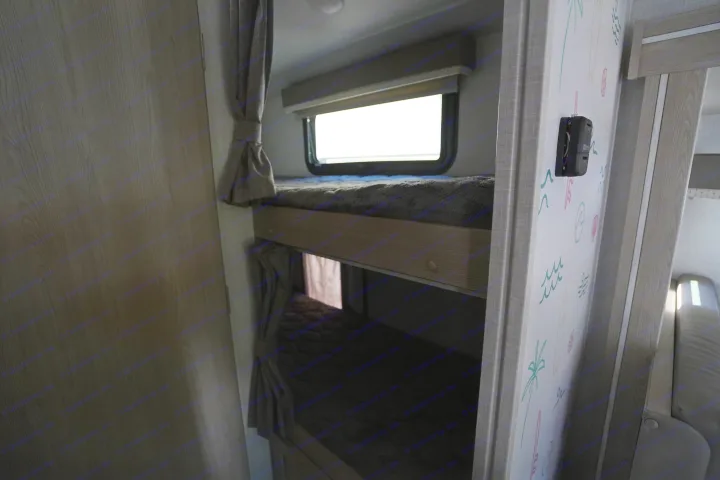 Cozy RV rental interior with bunk beds, a bright window, and playful wall decor. Ideal for family adventures.. Forest River Rockwood 2021