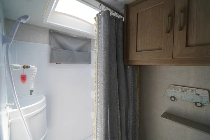 Inside an RV rental: compact bathroom with shower, curtain, sink, cabinets, and a fun seagull bus decor.. Forest River Rockwood 2021