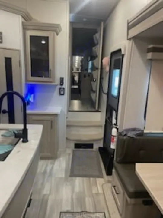 Inside an RV rental: kitchen counter, sink, cabinets, steps leading up, and a dinette booth. Ready for camping trips!. Forest River Rockwood Ultra Lite 2022