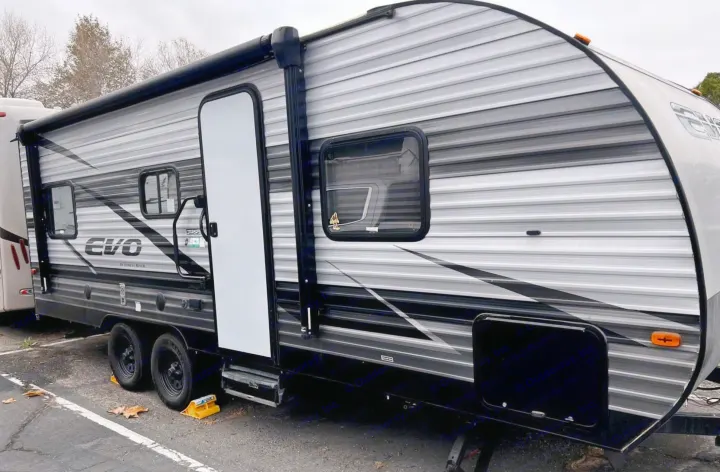 Grey and black Forest River EVO travel trailer RV rental, showing its exterior, awning, entry door, and windows.. Forest River EVO 208RD 2021