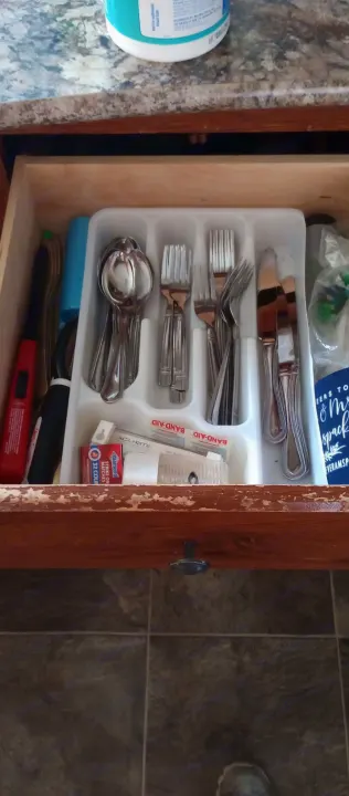 An RV rental kitchen drawer holds organized silverware, Band-Aids, matches, and a red lighter. Counter wipes are visible.. Keystone Hideout 2015