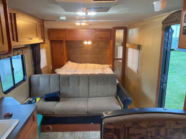 Inside a spacious RV rental: comfortable bed, sofa, and kitchen. Features include wood cabinets, windows, and an AC unit.. Forest River Cherokee Grey Wolf 2013