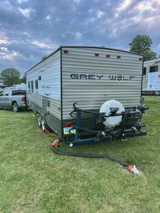 A Grey Wolf travel trailer, perfect for an RV rental, is parked at a grassy campsite, ready for adventure.. Forest River Cherokee Grey Wolf 2013