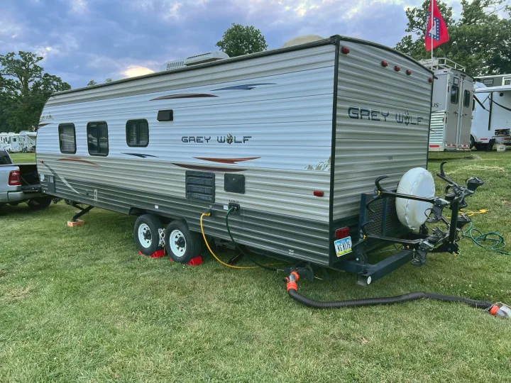 Grey Wolf travel trailer rv rental ready for use at a grassy site, featuring utility hookups & a bike rack.. Forest River Cherokee Grey Wolf 2013