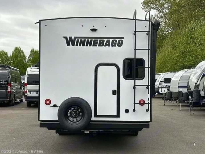 Rear view of a white Winnebago travel trailer, ideal for your next RV rental adventure, with a spare tire & ladder.. Winnebago Minnie 2301BHS 2024