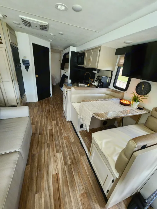 Modern RV rental interior: wood floors, dinette, kitchen, sofa, and bunk beds visible.. Thor A.C.E. 2018