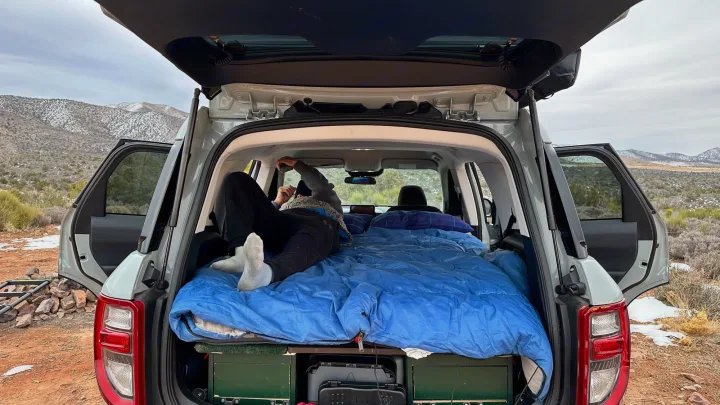 Cozy car camping setup inside an SUV, offering comfort for mountain road trips like an RV rental.. Ford Bronco Sport 2022