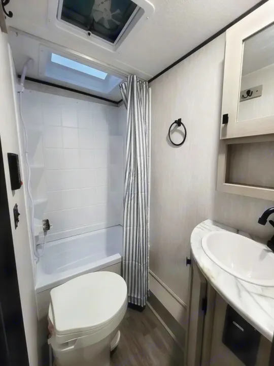 This rv rental features a compact, bright bathroom with a shower/tub, toilet, and sink vanity.. Coachmen Apex Nano 2024