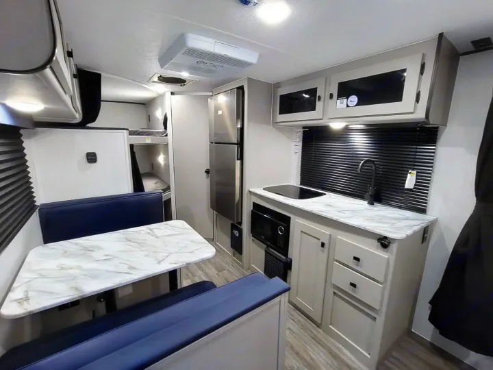RV rental: well-equipped kitchen with sink, stove, microwave, refrigerator, dinette, and bunk beds in this modern interior.. Coachmen Apex Nano 2024