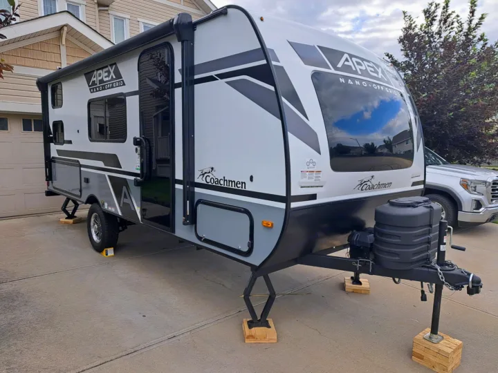 Modern white & gray Apex Nano Off Grid travel trailer, stabilized for an RV rental adventure. Parked on a driveway.. Coachmen Apex Nano 2024