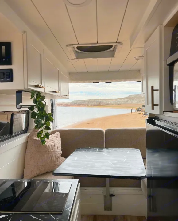 Inside an RV rental: a modern kitchen, comfortable dining area, and a stunning view of a lake beach.. Dodge Ram 1500 2019