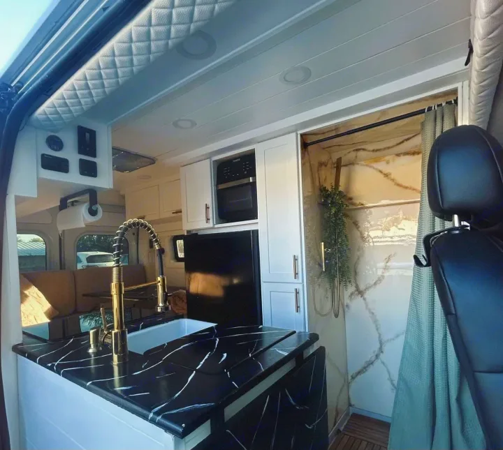 Step inside this luxurious rv rental! Features a sleek kitchen with black counters, gold faucet, & chic marbled shower.. Dodge Ram 1500 2019