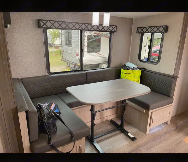 RV rental interior: a comfortable U-shaped dinette with dark quilted seating, an adjustable table, and outdoor views.. Coachmen fet257bhs-320 2021