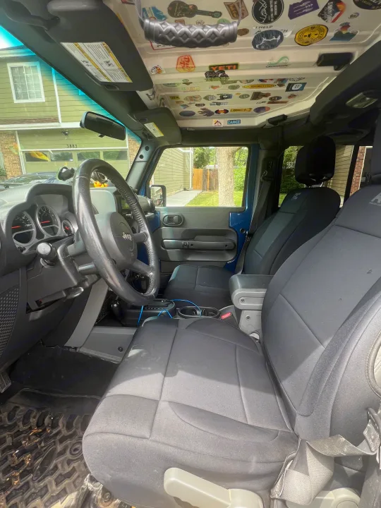 Inside a personalized blue Jeep, decked with adventure stickers on the roof. Perfect for an outdoor trip, like an rv rental journey.. Jeep Wrangler 2010