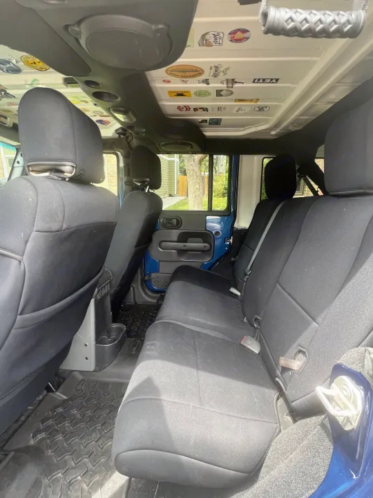 Jeep interior showing rear cloth seats, rugged rubber mats, and a custom sticker-covered ceiling. A versatile alternative to an rv rental.. Jeep Wrangler 2010