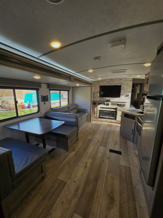 Modern RV rental interior with inviting dining, living, and kitchen areas, plus an entertainment center with fireplace.. Keystone RV Springdale 2021