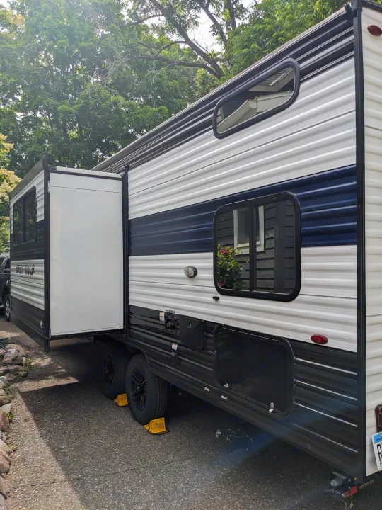 This large, black, white, and navy rv rental travel trailer is parked with its slide-out extended, ready for adventure.. Forest River Cherokee Grey Wolf 23DBH 2024
