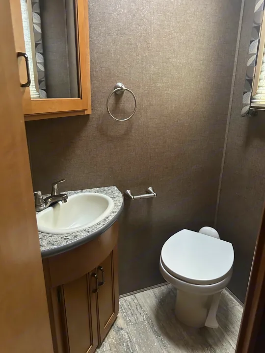 Clean RV rental bathroom featuring a sink, vanity, toilet, and mirrored cabinet. A practical and compact space.. Thor Hurricane 2017
