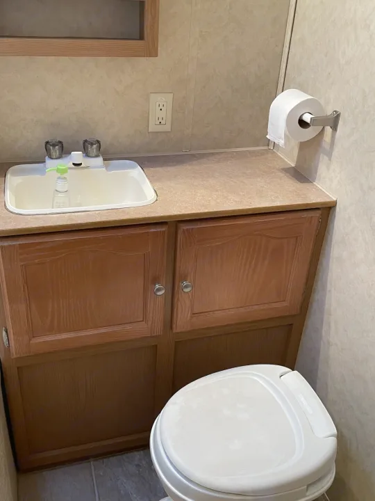 An RV rental's compact bathroom, complete with sink, toilet, and cabinetry.. Dutchmen Dutchmen 2007
