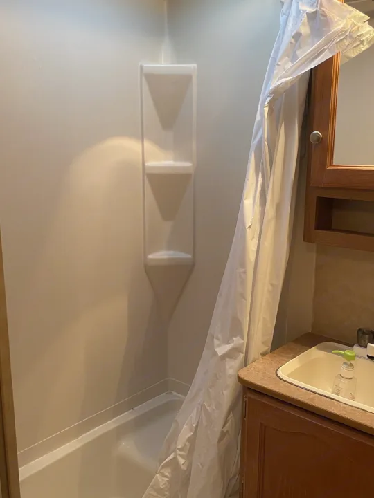 Inside an RV rental bathroom, showing a compact white shower/tub, shower curtain, and vanity with sink.. Dutchmen Dutchmen 2007