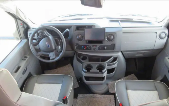 Clean RV rental front cabin showcasing a Ford dashboard, steering wheel, and two-tone quilted seats.. Forest River Sunseeker TS 2022