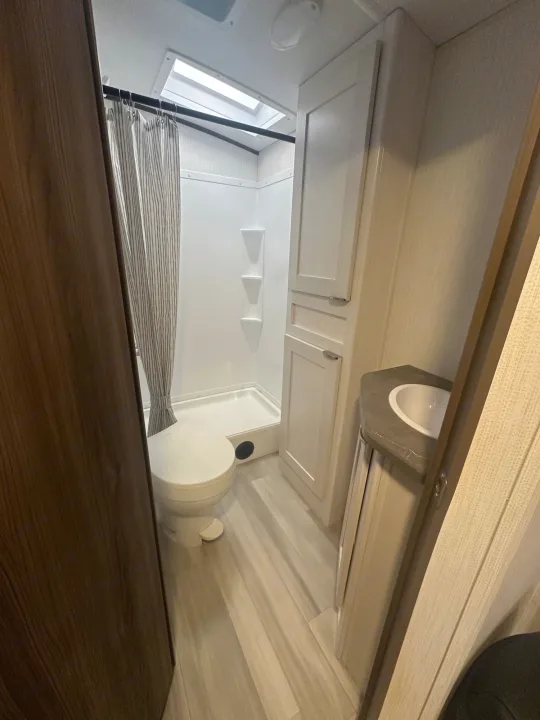 Compact RV rental bathroom features a shower, toilet, sink, and cabinet storage, designed for efficient travel.. Cruiser RV MPG 2500bh 2024