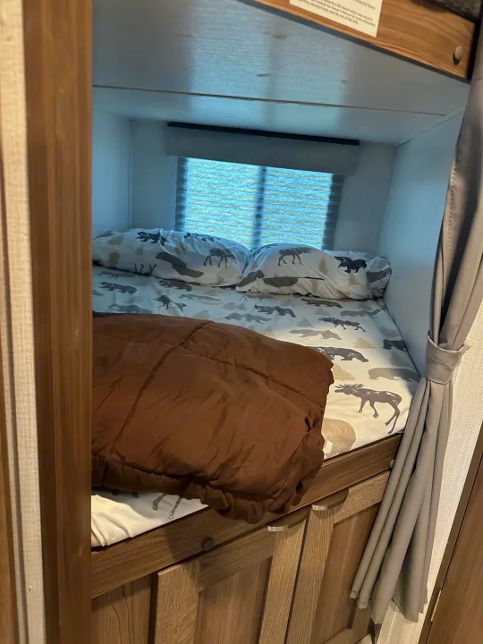 Cozy RV rental bunk bed with animal-patterned bedding and window blinds, perfect for a family adventure. Camper interior.. Cruiser RV MPG 2500bh 2024