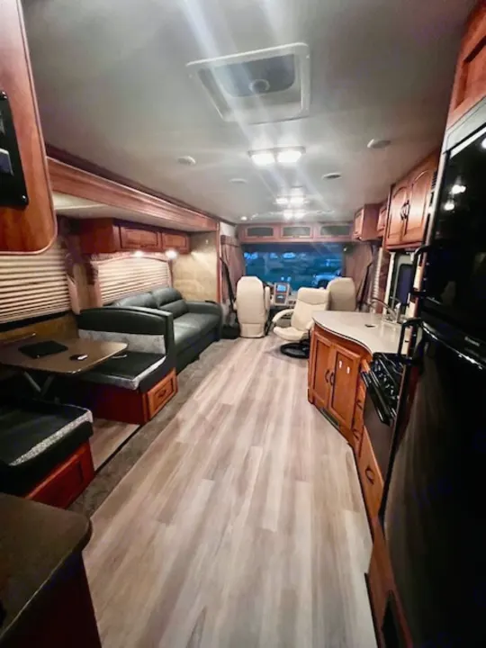 Spacious RV rental interior featuring a full kitchen, comfortable living area with couch, and dining booth, ready for your next adventure.. Forest River Coachmen Mirada 32 DSF 2011