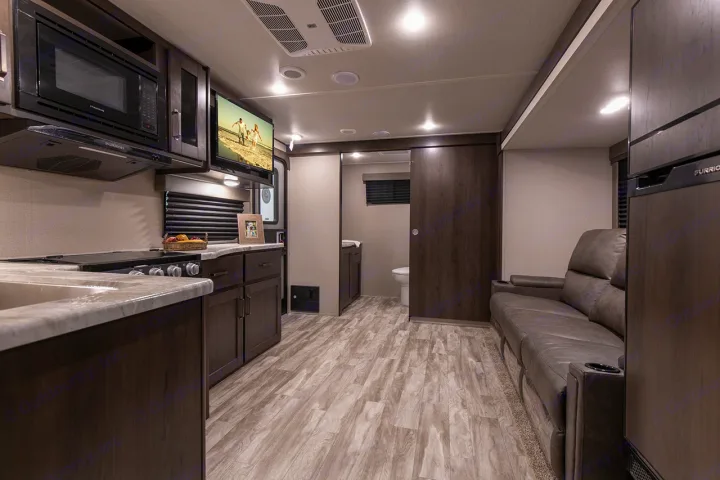 Spacious modern RV rental interior featuring a full kitchen, living area with sofa, and bathroom access.. Grand Design Transcend Xplor 221RB 2023