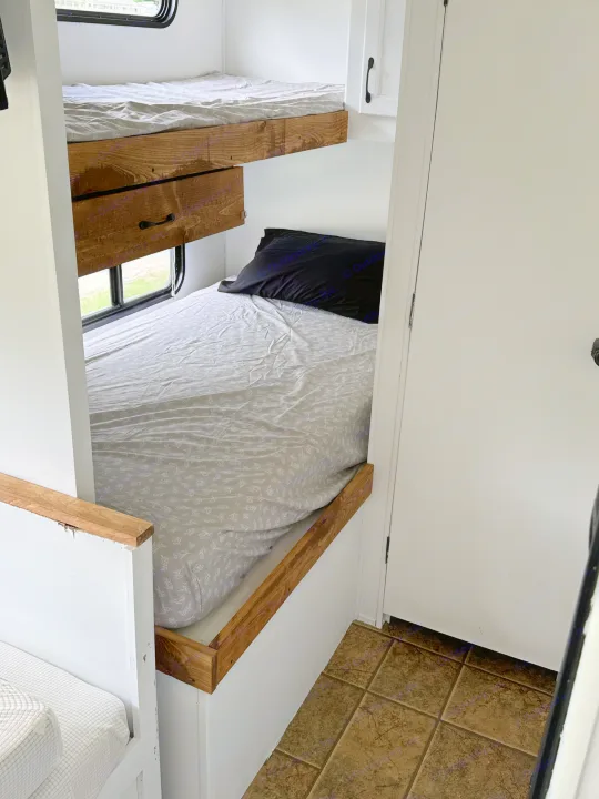 Cozy RV rental bunk beds with wood accents and a window. Perfect sleeping setup for family travel in your camper.. Forest River Cherokee Grey Wolf 2012