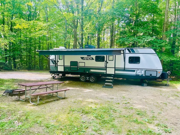 This RV rental is perfectly set up at a wooded campsite, complete with a picnic table and fire pit for outdoor enjoyment.. Coachmen Other 2022