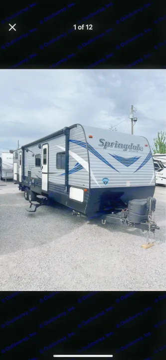 A grey Springdale travel trailer on a gravel lot under a cloudy sky. Consider this recreational vehicle for an RV rental.. Keystone RV Summerland 2018