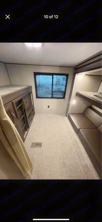 RV rental bunkhouse interior. Features multiple bunk beds, a window with blinds, and floor vent for comfortable mobile lodging.. Keystone RV Summerland 2018