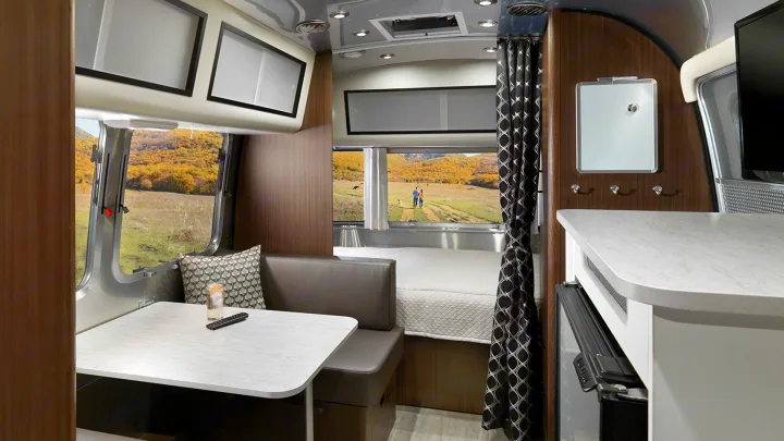Bright and inviting RV rental interior with a cozy dinette, comfortable bed, and scenic views for your next getaway.. Airstream Caravel 2022