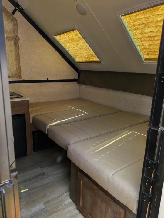 Cozy RV rental interior with a comfortable convertible bed, compact kitchen, and bright skylights, perfect for road trips.. Rockwood A122s 2023